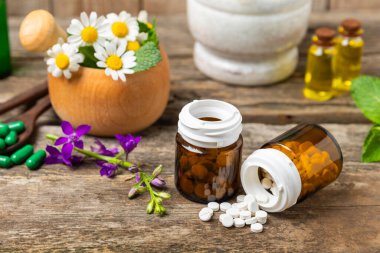 Ahşap zemin üzerinde alternatif ilaç bitkisel kapsül organik ilaç. Bitki ve tablet çeşitleri, vitaminler ve diyet takviyeleri. Sağlıklı yaşam için tıbbi ve şifalı bitkiler.