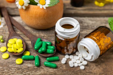 Ahşap zemin üzerinde alternatif ilaç bitkisel kapsül organik ilaç. Bitki ve tablet çeşitleri, vitaminler ve diyet takviyeleri. Sağlıklı yaşam için tıbbi ve şifalı bitkiler.