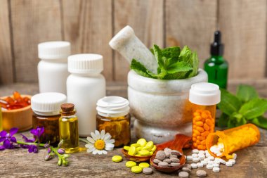 Ahşap zemin üzerinde alternatif ilaç bitkisel kapsül organik ilaç. Bitki ve tablet çeşitleri, vitaminler ve diyet takviyeleri. Sağlıklı yaşam için tıbbi ve şifalı bitkiler.