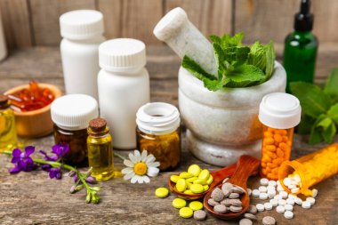 Ahşap zemin üzerinde alternatif ilaç bitkisel kapsül organik ilaç. Bitki ve tablet çeşitleri, vitaminler ve diyet takviyeleri. Sağlıklı yaşam için tıbbi ve şifalı bitkiler.