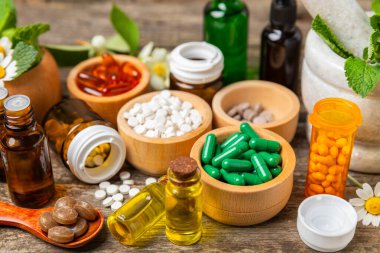 Ahşap zemin üzerinde alternatif ilaç bitkisel kapsül organik ilaç. Bitki ve tablet çeşitleri, vitaminler ve diyet takviyeleri. Sağlıklı yaşam için tıbbi ve şifalı bitkiler.