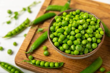 Ahşap zemin üzerinde yeşil bezelyeler olan taze bezelye kabukları. Tatlı yeşil bezelyeler. Yeşil bezelye fasulyesi sebzesi. Vejetaryen. Sağlıklı sebze. Boşluğu kopyala