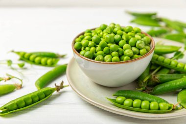 Ahşap zemin üzerinde yeşil bezelyeler olan taze bezelye kabukları. Tatlı yeşil bezelyeler. Yeşil bezelye fasulyesi sebzesi. Vejetaryen. Sağlıklı sebze. Boşluğu kopyala