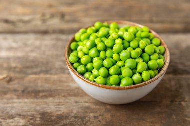 Ahşap zemin üzerinde yeşil bezelyeler olan taze bezelye kabukları. Tatlı yeşil bezelyeler. Yeşil bezelye fasulyesi sebzesi. Vejetaryen. Sağlıklı sebze. Boşluğu kopyala