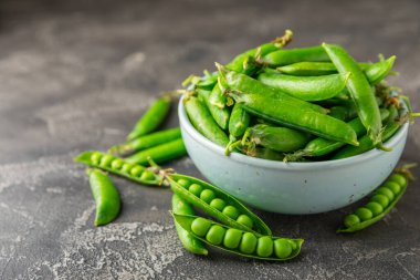 Ahşap zemin üzerinde yeşil bezelyeler olan taze bezelye kabukları. Tatlı yeşil bezelyeler. Yeşil bezelye fasulyesi sebzesi. Vejetaryen. Sağlıklı sebze. Boşluğu kopyala