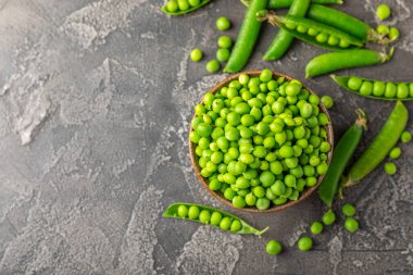 Ahşap zemin üzerinde yeşil bezelyeler olan taze bezelye kabukları. Tatlı yeşil bezelyeler. Yeşil bezelye fasulyesi sebzesi. Vejetaryen. Sağlıklı sebze. Boşluğu kopyala