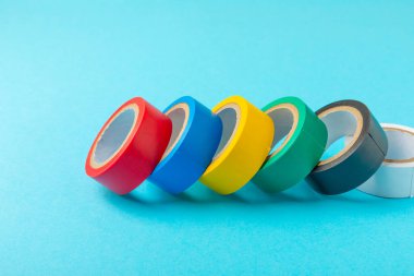 Parlak renkli arka plandaki bant yalıtılıyor. Farklı renkte izolasyon bantları. Yalıtım bandı. İnşaat aletleri. Elektrikçi aletleri. Bir parça koli bandı. Metin için boşluk. Boşluğu kopyala.