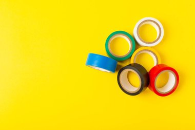 Parlak renkli arka plandaki bant yalıtılıyor. Farklı renkte izolasyon bantları. Yalıtım bandı. İnşaat aletleri. Elektrikçi aletleri. Bir parça koli bandı. Metin için boşluk. Boşluğu kopyala.