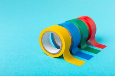 Parlak renkli arka plandaki bant yalıtılıyor. Farklı renkte izolasyon bantları. Yalıtım bandı. İnşaat aletleri. Elektrikçi aletleri. Bir parça koli bandı. Metin için boşluk. Boşluğu kopyala.