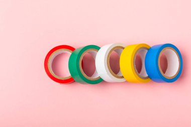 Parlak renkli arka plandaki bant yalıtılıyor. Farklı renkte izolasyon bantları. Yalıtım bandı. İnşaat aletleri. Elektrikçi aletleri. Bir parça koli bandı. Metin için boşluk. Boşluğu kopyala.