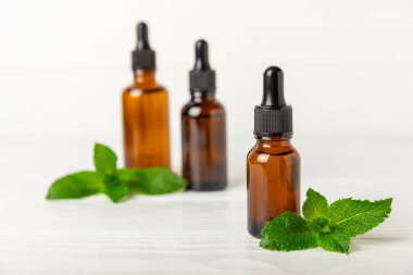 Ahşap bir arka planda esaslı bir nane şekeri. Naneli esaslı yağ ve taze nane yaprakları. Bir şişe aromaterapi yağı. Nane özütü. Doğal kozmetik konsepti, spa bakımı. Boşluğu kopyala