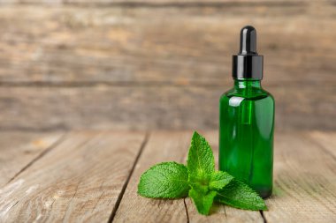 Ahşap bir arka planda esaslı bir nane şekeri. Naneli esaslı yağ ve taze nane yaprakları. Bir şişe aromaterapi yağı. Nane özütü. Doğal kozmetik konsepti, spa bakımı. Boşluğu kopyala