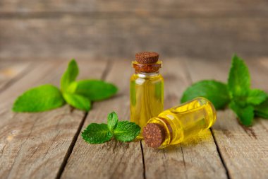 Ahşap bir arka planda esaslı bir nane şekeri. Naneli esaslı yağ ve taze nane yaprakları. Bir şişe aromaterapi yağı. Nane özütü. Doğal kozmetik konsepti, spa bakımı. Boşluğu kopyala