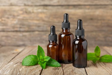 Ahşap bir arka planda esaslı bir nane şekeri. Naneli esaslı yağ ve taze nane yaprakları. Bir şişe aromaterapi yağı. Nane özütü. Doğal kozmetik konsepti, spa bakımı. Boşluğu kopyala