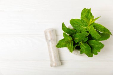 Ahşap zemin üzerinde havan ve kabuk ile taze nane. Melissa gider. Şifalı bitkiler, ilaç için havanda yeşil nane yaprakları. Mesaj için alan. Boşluğu kopyala.