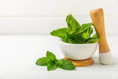 Ahşap zemin üzerinde havan ve kabuk ile taze nane. Melissa gider. Şifalı bitkiler, ilaç için havanda yeşil nane yaprakları. Mesaj için alan. Boşluğu kopyala.