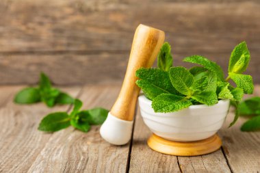 Ahşap zemin üzerinde havan ve kabuk ile taze nane. Melissa gider. Şifalı bitkiler, ilaç için havanda yeşil nane yaprakları. Mesaj için alan. Boşluğu kopyala.