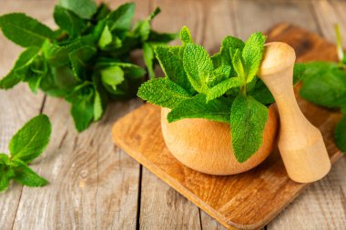 Ahşap zemin üzerinde havan ve kabuk ile taze nane. Melissa gider. Şifalı bitkiler, ilaç için havanda yeşil nane yaprakları. Mesaj için alan. Boşluğu kopyala.