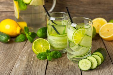 Salatalık suyu, limon, nane ve ahşap bir masada. İçme bardağında dilimlenmiş salatalık ile karıştırılmış su. Tonik ferahlatıcı bir içecek. Salatalık limonata. Doğal soğutma içeceği. Boşluğu kopyala.