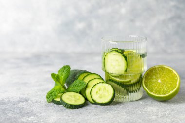 Salatalık suyu, limon, nane ve ahşap bir masada. İçme bardağında dilimlenmiş salatalık ile karıştırılmış su. Tonik ferahlatıcı bir içecek. Salatalık limonata. Doğal soğutma içeceği. Boşluğu kopyala.