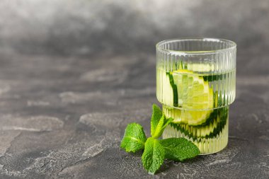 Salatalık suyu, limon, nane ve ahşap bir masada. İçme bardağında dilimlenmiş salatalık ile karıştırılmış su. Tonik ferahlatıcı bir içecek. Salatalık limonata. Doğal soğutma içeceği. Boşluğu kopyala.
