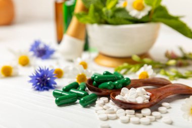 Ahşap zemin üzerinde alternatif ilaç bitkisel kapsül organik ilaç. Bitki ve tablet çeşitleri, vitaminler ve diyet takviyeleri. Sağlıklı yaşam için tıbbi ve şifalı bitkiler.
