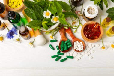 Ahşap zemin üzerinde alternatif ilaç bitkisel kapsül organik ilaç. Bitki ve tablet çeşitleri, vitaminler ve diyet takviyeleri. Sağlıklı yaşam için tıbbi ve şifalı bitkiler.