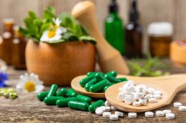 Ahşap zemin üzerinde alternatif ilaç bitkisel kapsül organik ilaç. Bitki ve tablet çeşitleri, vitaminler ve diyet takviyeleri. Sağlıklı yaşam için tıbbi ve şifalı bitkiler.