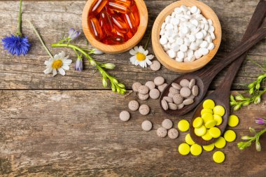 Ahşap zemin üzerinde alternatif ilaç bitkisel kapsül organik ilaç. Bitki ve tablet çeşitleri, vitaminler ve diyet takviyeleri. Sağlıklı yaşam için tıbbi ve şifalı bitkiler.