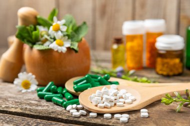 Ahşap zemin üzerinde alternatif ilaç bitkisel kapsül organik ilaç. Bitki ve tablet çeşitleri, vitaminler ve diyet takviyeleri. Sağlıklı yaşam için tıbbi ve şifalı bitkiler.