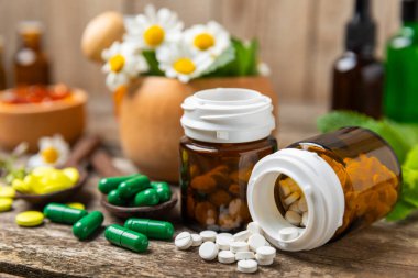 Ahşap zemin üzerinde alternatif ilaç bitkisel kapsül organik ilaç. Bitki ve tablet çeşitleri, vitaminler ve diyet takviyeleri. Sağlıklı yaşam için tıbbi ve şifalı bitkiler.