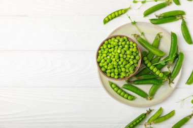 Ahşap zemin üzerinde yeşil bezelyeler olan taze bezelye kabukları. Tatlı yeşil bezelyeler. Yeşil bezelye fasulyesi sebzesi. Vejetaryen. Sağlıklı sebze. Boşluğu kopyala