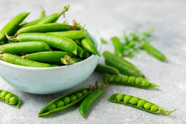 Ahşap zemin üzerinde yeşil bezelyeler olan taze bezelye kabukları. Tatlı yeşil bezelyeler. Yeşil bezelye fasulyesi sebzesi. Vejetaryen. Sağlıklı sebze. Boşluğu kopyala