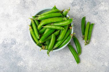 Ahşap zemin üzerinde yeşil bezelyeler olan taze bezelye kabukları. Tatlı yeşil bezelyeler. Yeşil bezelye fasulyesi sebzesi. Vejetaryen. Sağlıklı sebze. Boşluğu kopyala