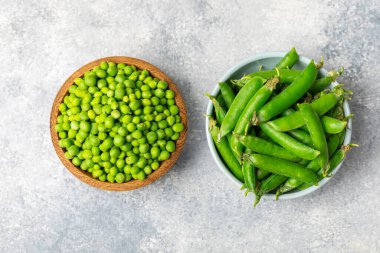 Ahşap zemin üzerinde yeşil bezelyeler olan taze bezelye kabukları. Tatlı yeşil bezelyeler. Yeşil bezelye fasulyesi sebzesi. Vejetaryen. Sağlıklı sebze. Boşluğu kopyala