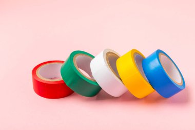 Parlak renkli arka plandaki bant yalıtılıyor. Farklı renkte izolasyon bantları. Yalıtım bandı. İnşaat aletleri. Elektrikçi aletleri. Bir parça koli bandı. Metin için boşluk. Boşluğu kopyala.