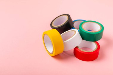 Parlak renkli arka plandaki bant yalıtılıyor. Farklı renkte izolasyon bantları. Yalıtım bandı. İnşaat aletleri. Elektrikçi aletleri. Bir parça koli bandı. Metin için boşluk. Boşluğu kopyala.