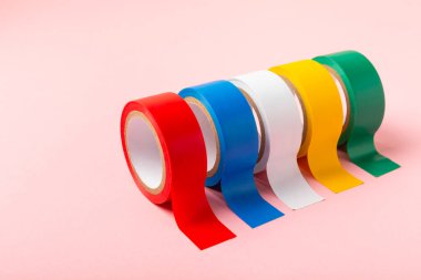 Parlak renkli arka plandaki bant yalıtılıyor. Farklı renkte izolasyon bantları. Yalıtım bandı. İnşaat aletleri. Elektrikçi aletleri. Bir parça koli bandı. Metin için boşluk. Boşluğu kopyala.