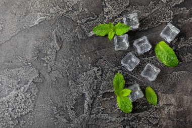 Arka planda nane ve buz var. Yeşil taze nane ve buz küpü. Nane yaprağı, buz küpü ve soğuk içecek için su damlası. Üst Manzara. Mesaj için yer var. Boşluğu kopyala.