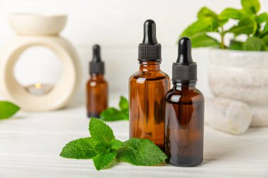 Ahşap bir arka planda esaslı bir nane şekeri. Naneli esaslı yağ ve taze nane yaprakları. Bir şişe aromaterapi yağı. Nane özütü. Doğal kozmetik konsepti, spa bakımı. Boşluğu kopyala