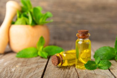 Ahşap bir arka planda esaslı bir nane şekeri. Naneli esaslı yağ ve taze nane yaprakları. Bir şişe aromaterapi yağı. Nane özütü. Doğal kozmetik konsepti, spa bakımı. Boşluğu kopyala