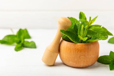 Ahşap zemin üzerinde havan ve kabuk ile taze nane. Melissa gider. Şifalı bitkiler, ilaç için havanda yeşil nane yaprakları. Mesaj için alan. Boşluğu kopyala.