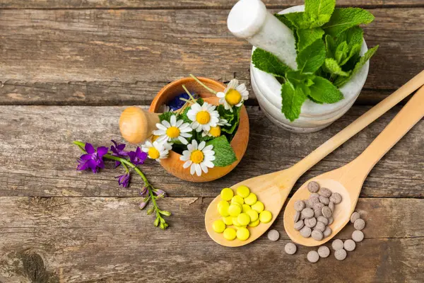 Ahşap zemin üzerinde alternatif ilaç bitkisel kapsül organik ilaç. Bitki ve tablet çeşitleri, vitaminler ve diyet takviyeleri. Sağlıklı yaşam için tıbbi ve şifalı bitkiler.