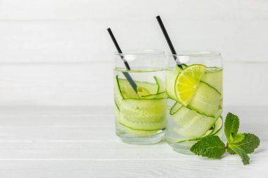 Salatalık suyu, limon, nane ve ahşap bir masada. İçme bardağında dilimlenmiş salatalık ile karıştırılmış su. Tonik ferahlatıcı bir içecek. Salatalık limonata. Doğal soğutma içeceği. Boşluğu kopyala.