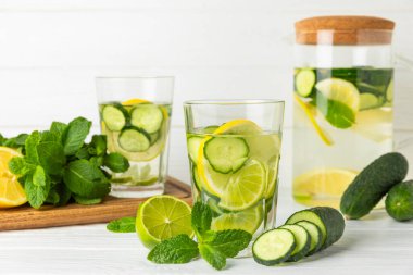 Salatalık suyu, limon, nane ve ahşap bir masada. İçme bardağında dilimlenmiş salatalık ile karıştırılmış su. Tonik ferahlatıcı bir içecek. Salatalık limonata. Doğal soğutma içeceği. Boşluğu kopyala.