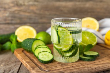 Salatalık suyu, limon, nane ve ahşap bir masada. İçme bardağında dilimlenmiş salatalık ile karıştırılmış su. Tonik ferahlatıcı bir içecek. Salatalık limonata. Doğal soğutma içeceği. Boşluğu kopyala.