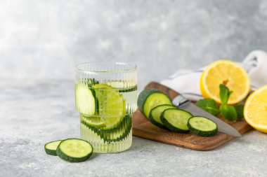 Salatalık suyu, limon, nane ve ahşap bir masada. İçme bardağında dilimlenmiş salatalık ile karıştırılmış su. Tonik ferahlatıcı bir içecek. Salatalık limonata. Doğal soğutma içeceği. Boşluğu kopyala.