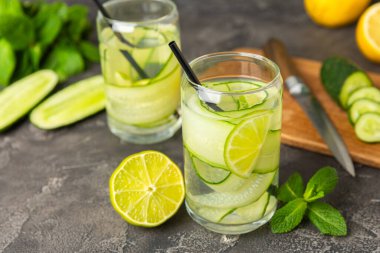 Salatalık suyu, limon, nane ve ahşap bir masada. İçme bardağında dilimlenmiş salatalık ile karıştırılmış su. Tonik ferahlatıcı bir içecek. Salatalık limonata. Doğal soğutma içeceği. Boşluğu kopyala.