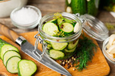 Ahşap bir arka planda kavanozda taze tuzlanmış ev yapımı salatalıklar. Dereotlu, sarımsaklı ve biberli salatalık turşusu. Konserve salatalık, salatalık ve penis. Ev yapımı koruma..