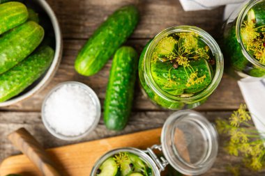 Ahşap bir arka planda kavanozda taze tuzlanmış ev yapımı salatalıklar. Dereotlu, sarımsaklı ve biberli salatalık turşusu. Konserve salatalık, salatalık ve penis. Ev yapımı koruma..